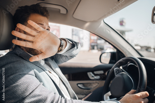 Young driver hides his face and looks scared because of dangerous traffic situation that could cause sar accident.