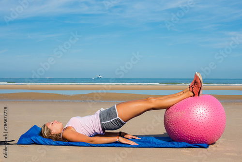 beautiful woman doing pilate ball on the sunny beach photo