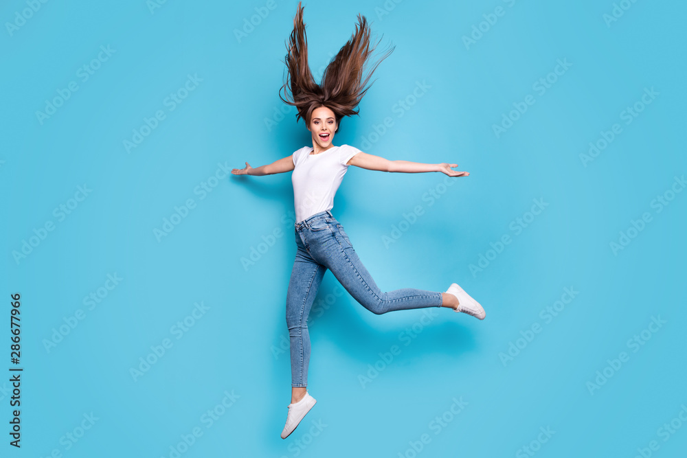 Full body photo of funny lady raising hands laughing wearing white t-shirt denim jeans isolated over blue background Full body photo of funny lady raising hands laughing wearing white t-shirt denim jeans isolated over blue background