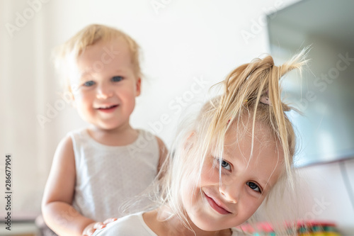 Cute adorable blond caucaian little sister hugging her toddler brother.couple of cheerful sibling playing indoor. Cute girl and baby boy enjoy relaxing at home. Happy childhood, family love, and care