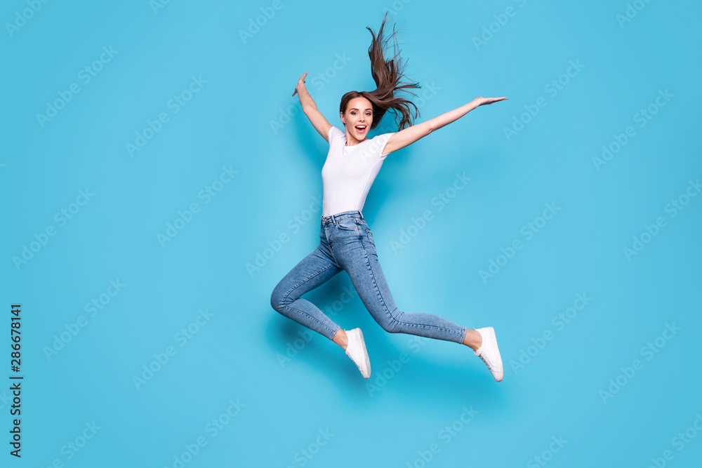 Full body photo of lovely girl raising hands arms jumping screaming isolated over blue background