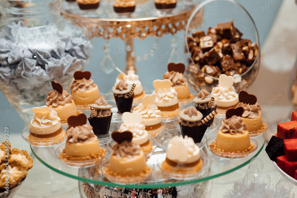 Sweet buffet for birthday party or wedding. Delicious wedding reception candy bar dessert table, cake. Delicious cupcakes with cream cheese frosting, candies and meringues.