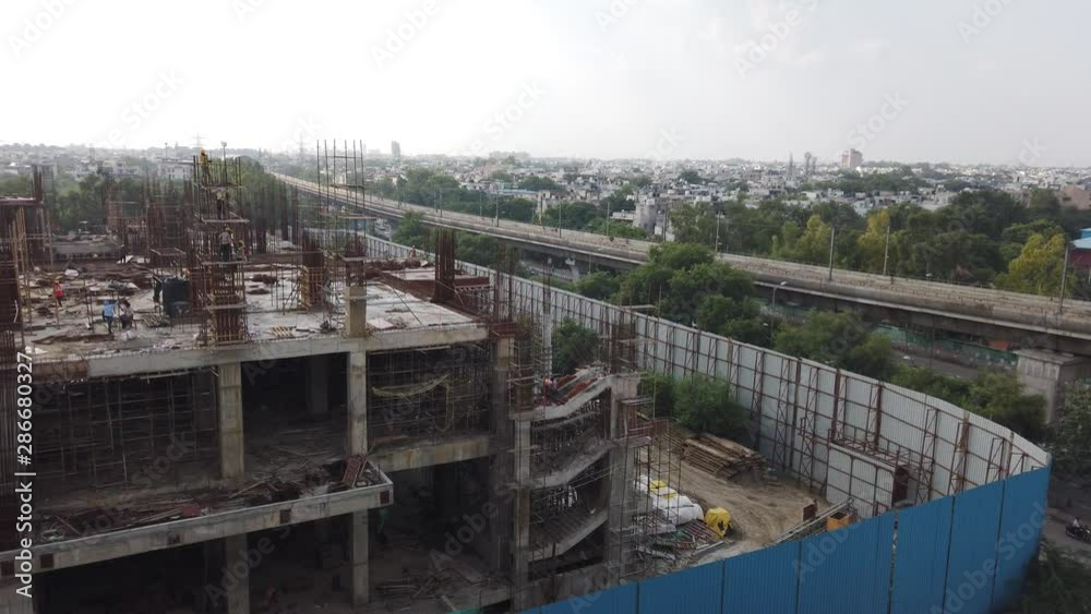 Panning view of metro line running parallel to Massive high-rise commercial building under-construction project in the CBD and business hub in national capital of New Delhi, India from a top floor. Panning view of metro line running parallel to Massive high-rise commercial building under-construction project in the CBD and business hub in national capital of New Delhi, India from a top floor.