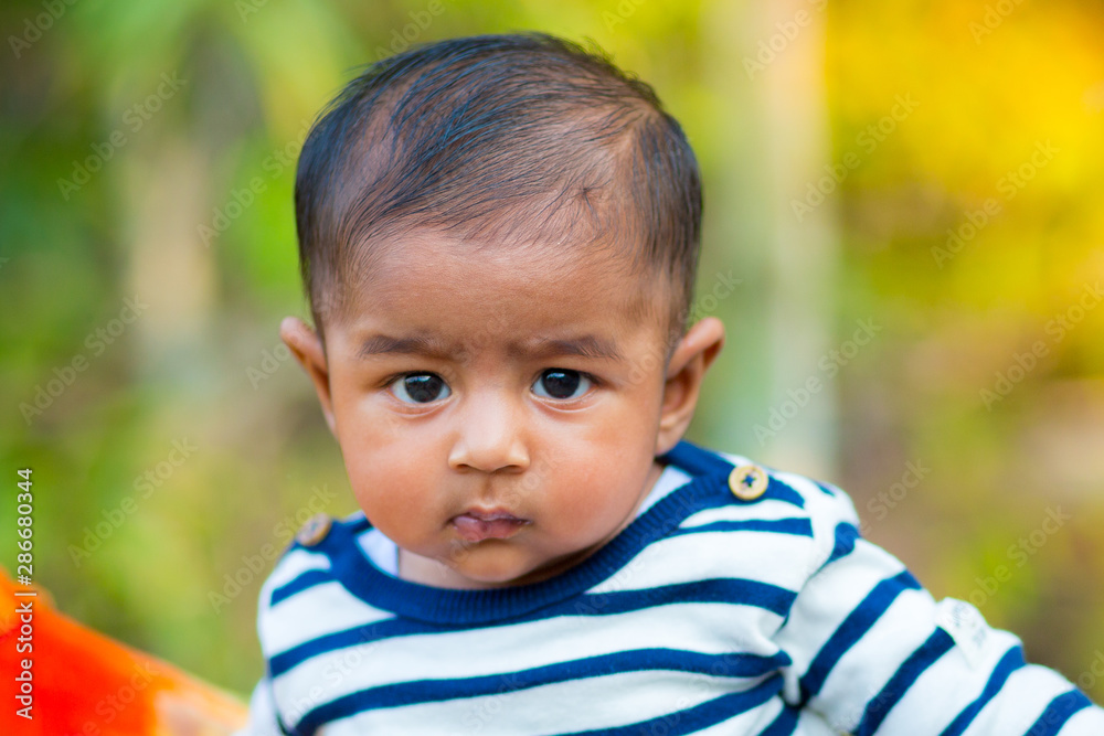 A baby boy looking and smiling. Dressed are white and navy blue striped dress. Baby candid shoot. Baby portrait. A baby boy looking and smiling. Dressed are white and navy blue striped dress. Baby candid shoot. Baby portrait.