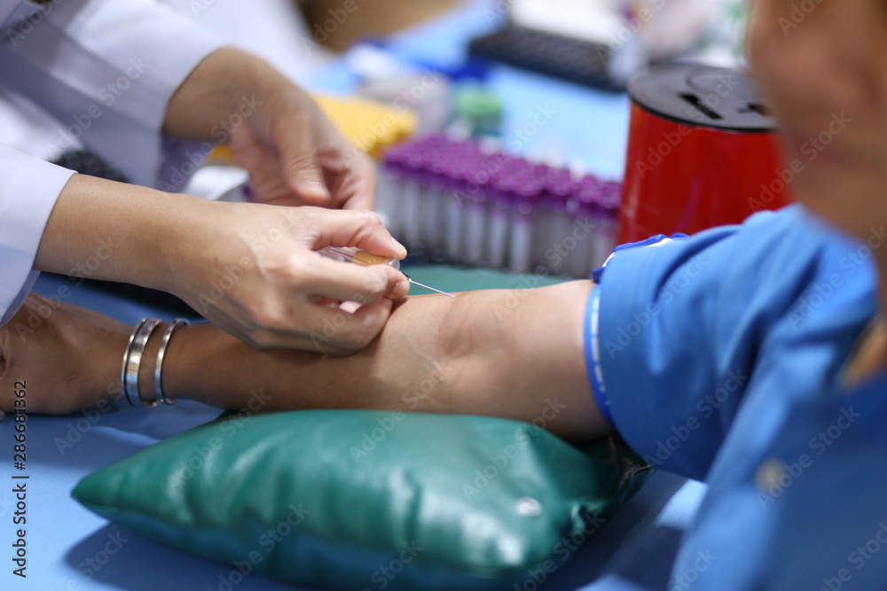 Thailand, Bangkok 2019/08/28. A health worker taking a blood sample from the vein by piercing the veinpunture and collecting blood into a test tube under negative pressure.