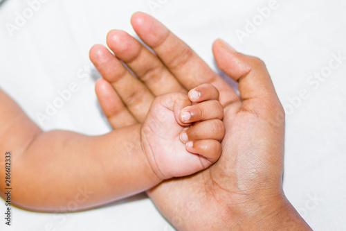 A new born baby's soft hand on mother's hand on a white background.