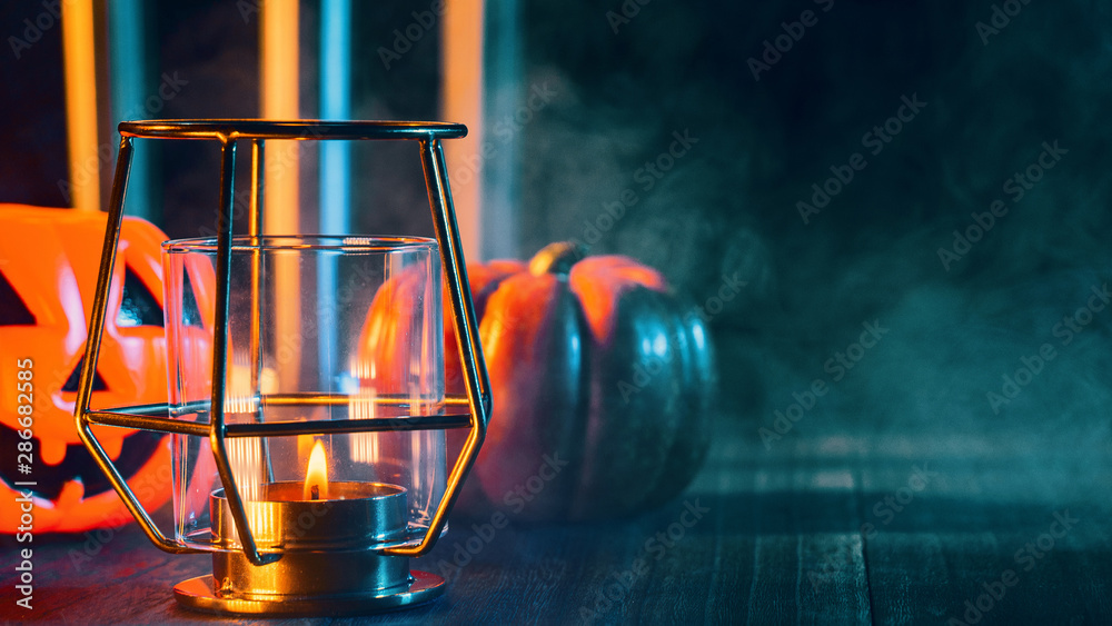 Halloween concept, spooky decorations with lighting up candle and candle holder with green tone smoke around on a dark wooden table, close up.