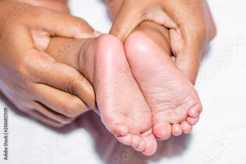 A mom holding baby’s two feet on a white background.