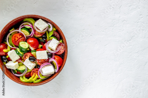 Greek salad on a concrete background. Tomatoes, peppers, olives, cheese, onions. Healthy eating. Diet. Vegetarian food.