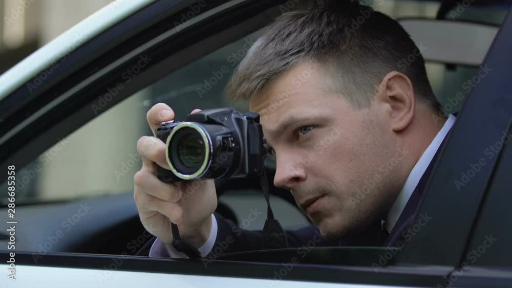 Male agent secretly taking photo by camera sitting in car, photojournalism Male agent secretly taking photo by camera sitting in car, photojournalism