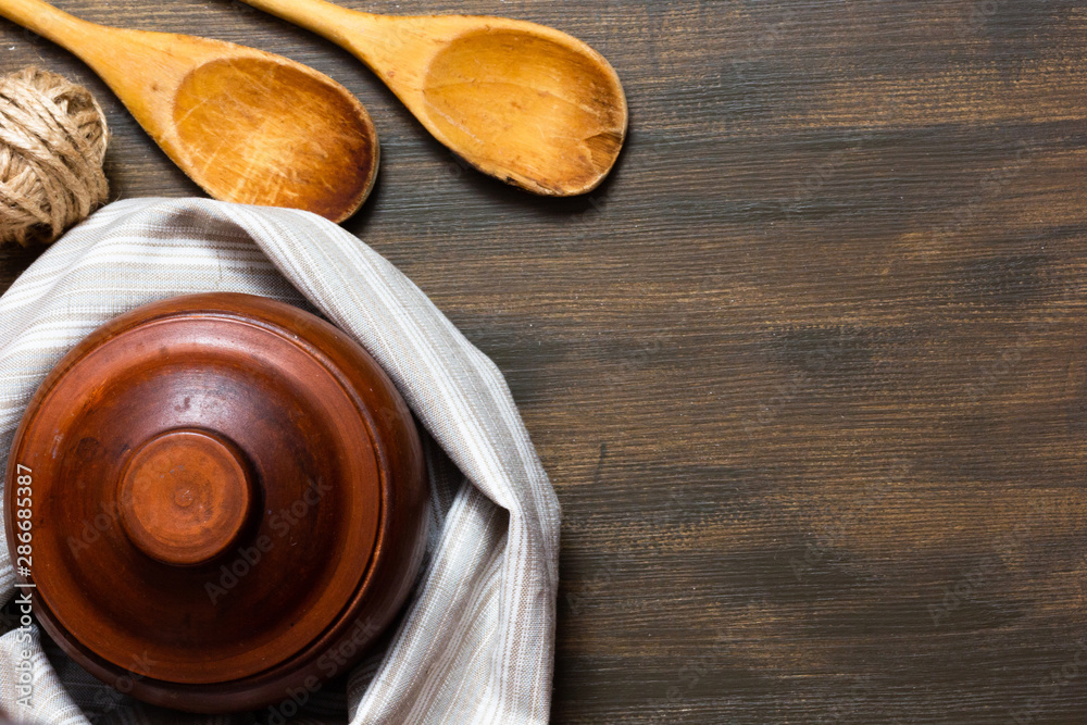 Top view of clay pot and wooden spoons on wooden background with copy space Top view of clay pot and wooden spoons on wooden background with copy space