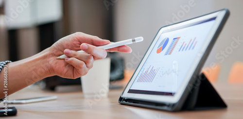 close up salesman employee hand using stylus pen to pointing on tablet screen to show company profit monthly in the meeting event at conference room , business strategy concept photo