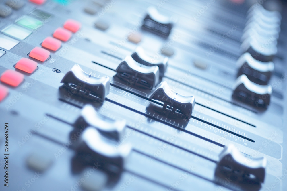 Fototapeta premium Audio mixer control panel with sliders in blur