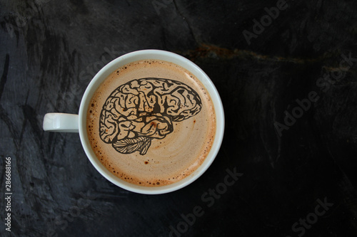 white cup with cappuccino and foam in the form of a silhouette of the brain on a Fototapet
