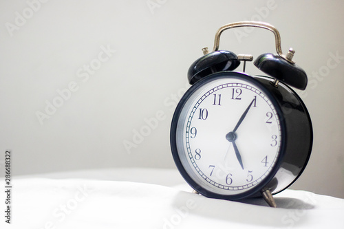 Antique black clock on the table with white linen