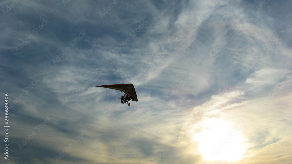 hang glider in the blue sky with milky clouds