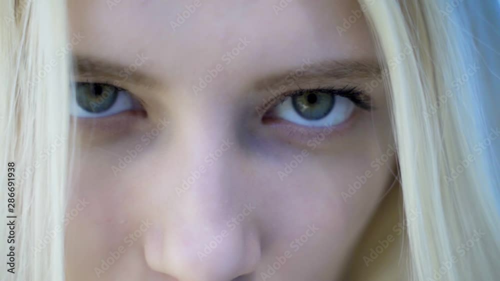 Green-blue eyes of a blonde girl close-up. Slow motion