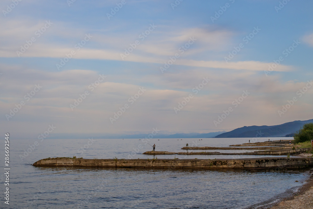 Lake Baikal. On breakwaters, fishermen catch fish with fishing rods.
