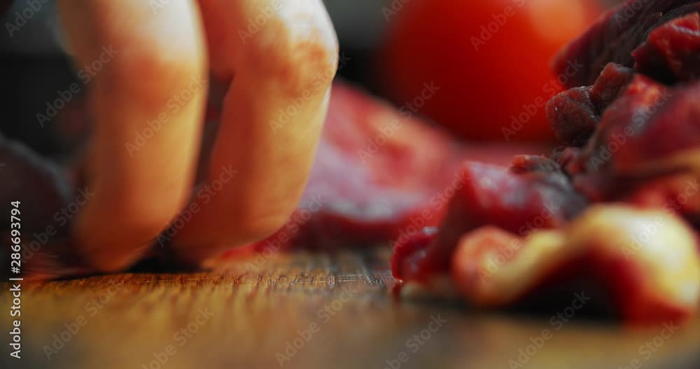 Woman cuts beef meat with black knife on wooden board. Bright red VIP beef, from the most beautiful cows Woman cuts beef meat with black knife on wooden board. Bright red VIP beef, from the most beautiful cows
