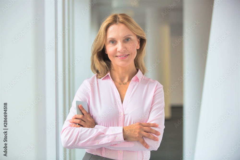 Portrait of confident businesswoman standing with arms crossed in corridor at office Portrait of confident businesswoman standing with arms crossed in corridor at office