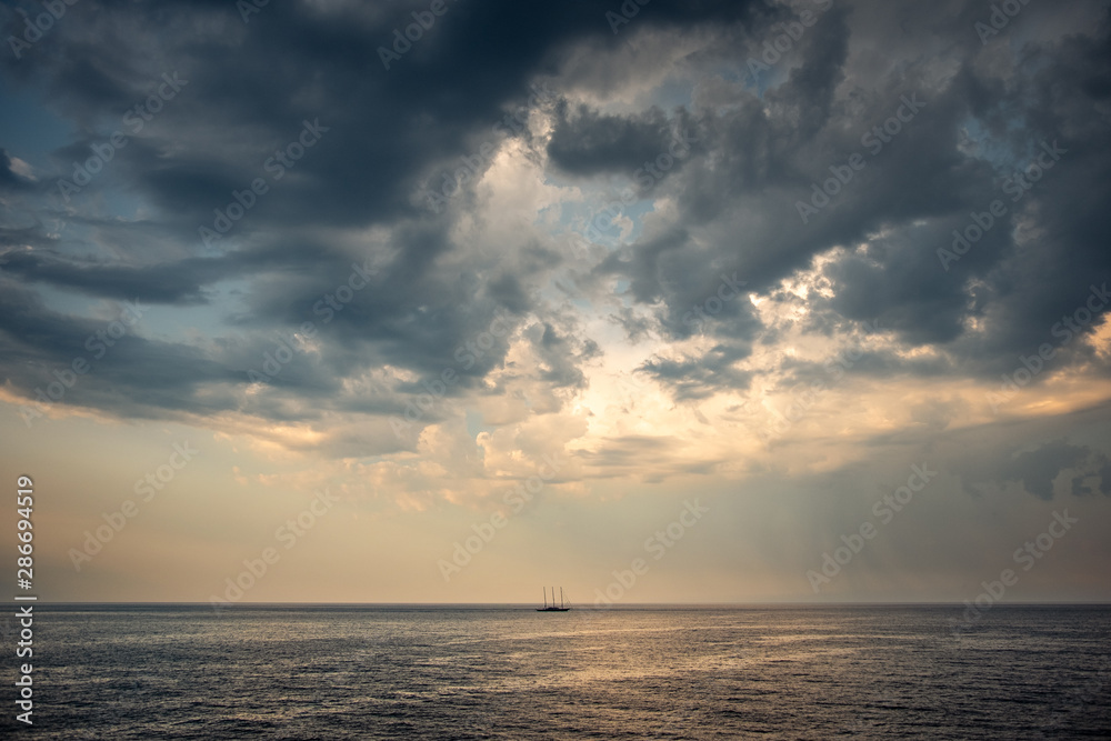 Moody clouds above lonely boat far out to sea off the coast of Croatia in the Adriatic Sea
