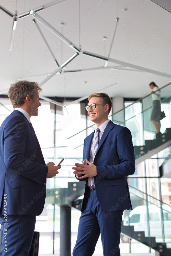 Businessmen discussing while standing at new office Businessmen discussing while standing at new office