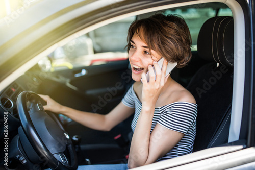 Tablou pe pânză Young pretty woman with telephone having phone conversation while driving car