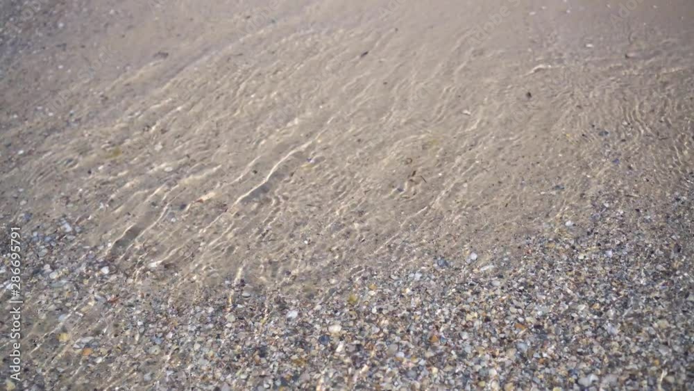Clear calm sea, coastline. Small waves slowly roll onto the sandy shore. Clear calm sea, coastline. Small waves slowly roll onto the sandy shore.