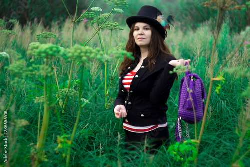 A woman in a tall hat with a purple backpack in the Park.