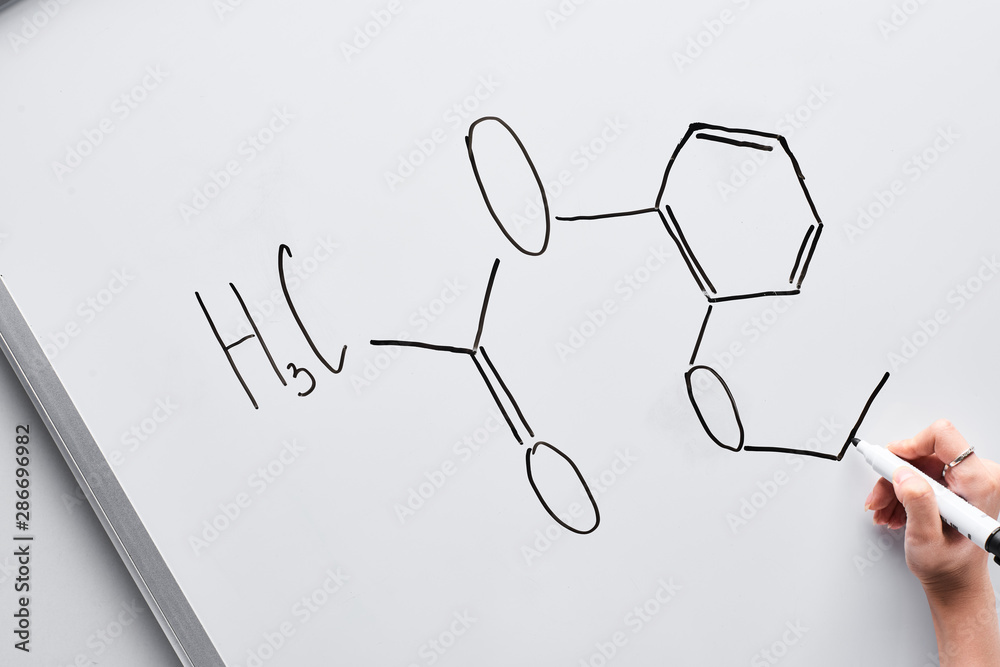 Fototapeta premium cropped view of woman writing chemical formula on white board