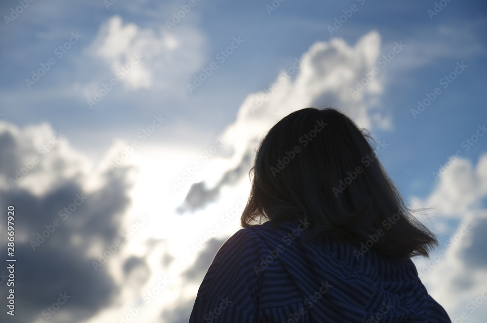 Woman look at cloudy sky, cumulus clouds lights in sun rays