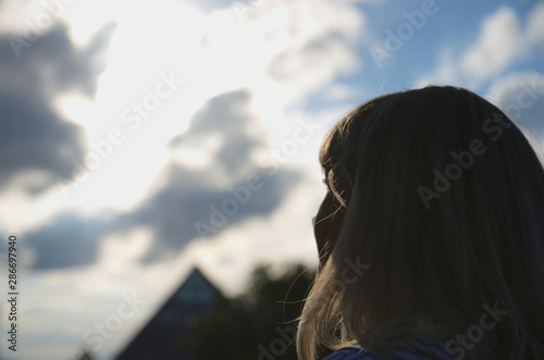 Woman look at cloudy sky, cumulus clouds lights in sun rays, pyramid at horizon