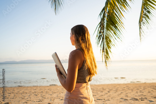 freelancer girl among tropical palm trees work on the island