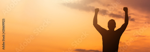 Foto Silhouette of a man with hands raised in the sunset.