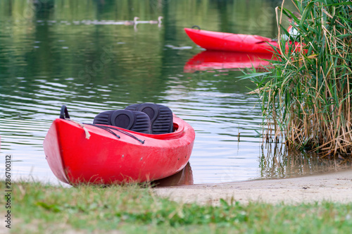 Red kayak by the shore of a river. Selective focus.