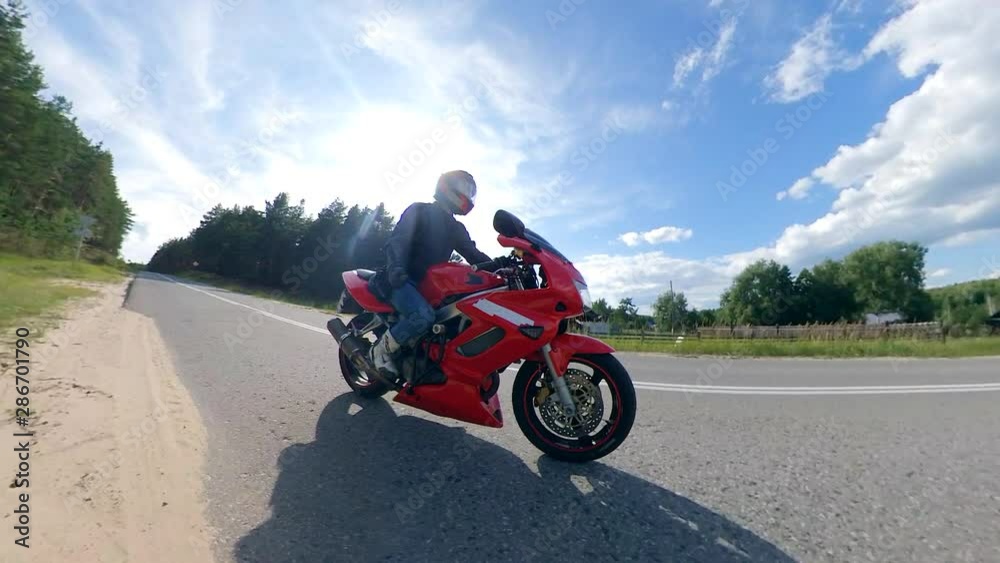Motorcycle on a road. Red motorbike in motion with the driver on it Motorcycle on a road. Red motorbike in motion with the driver on it