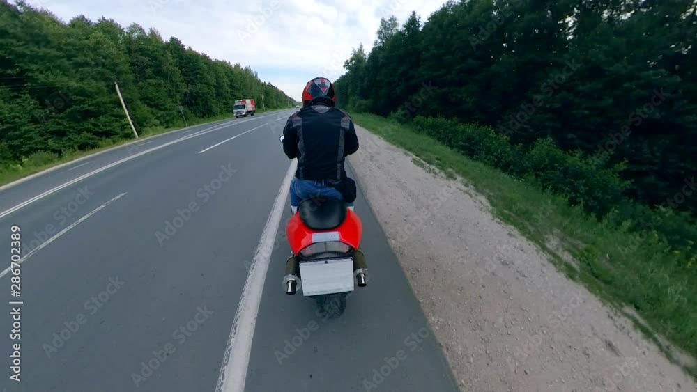 Motorcyclist starts driving along the highway. Motorcycle on a road.