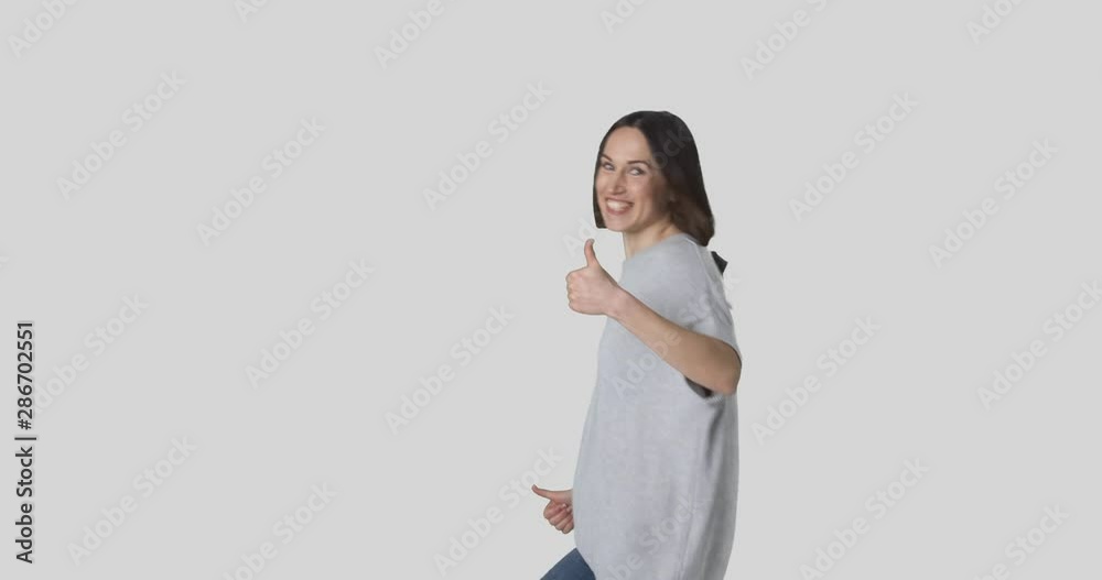 Happy young woman dancing and giving thumbs up over white background Happy young woman dancing and giving thumbs up over white background