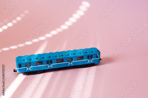Model of a Russian metro car on a pink background with sunlight. Russian transport. Toy model