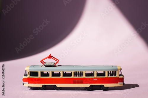 Model of a Russian tram on a pink background with sunlight. Russian transport. Toy model
