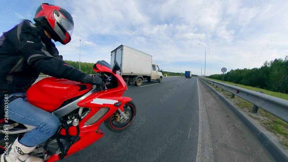 Side view of the driver riding the motorcycle along the highroad. Motorcycle on a road. Side view of the driver riding the motorcycle along the highroad. Motorcycle on a road.