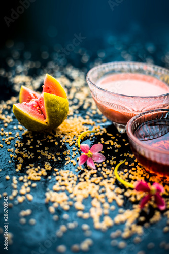 Guava face mask for dry skin on a wooden surface with vivid colors i.e., guava pulp, egg yolk, oatmeal, and some raw organic honey well mixed in a glass bowl along with raw ones. photo