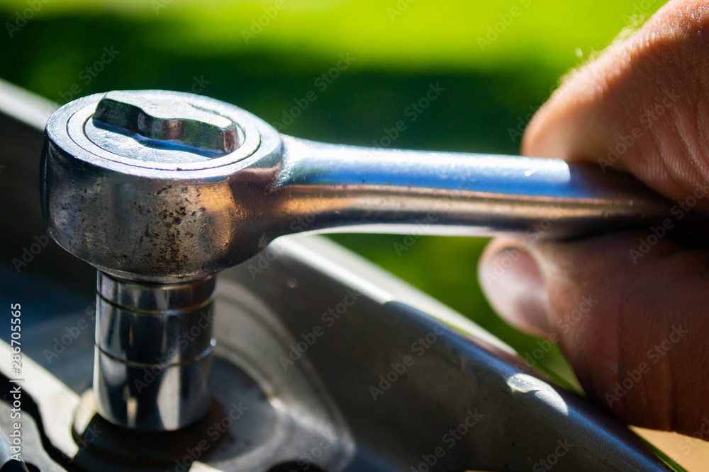 Obraz premium mechanik wykonujący naprawę samochodową kluczem nasadowym