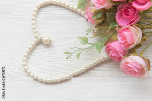 Pearl necklace with pink rose on the white background, vintage tone.  Lifestyle Concept
