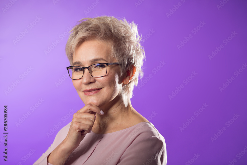 portrait of adult woman in glasses with short haircut on purple background portrait of adult woman in glasses with short haircut on purple background