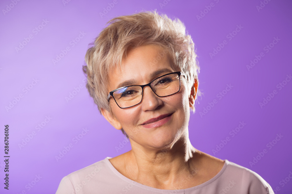 portrait of adult woman in glasses with short haircut on purple background