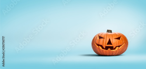 An unlit Halloween Jack O Lantern isolated on a widescreen pale blue background photo