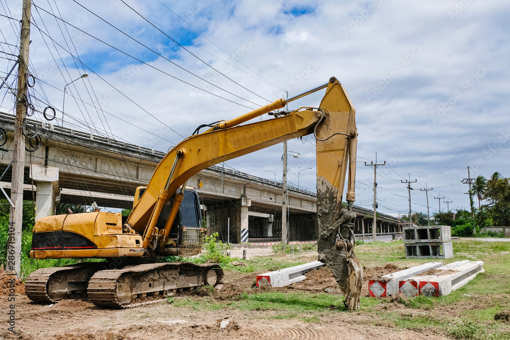 Excavator with stack of concrete electricity pillar in construction site. Excavator with stack of concrete electricity pillar in construction site.