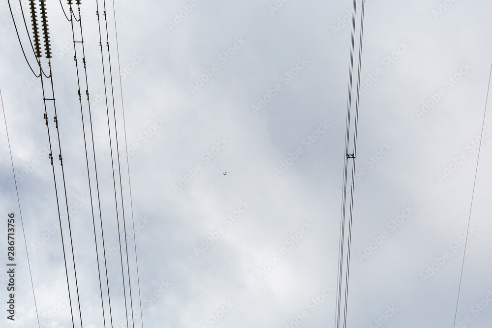Tiny cessna plane high above power pylon. Tiny cessna plane high above power pylon.