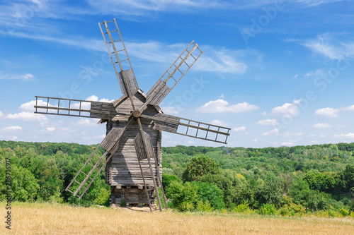 Old Rare Ancient Wooden Windmill in front of Cloud Sky